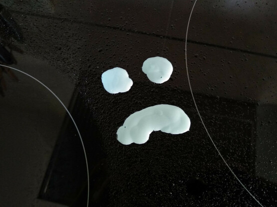 Detall d'un dibuix d'una cara trista fet amb producte de neteja sobre una placa d'inducció.